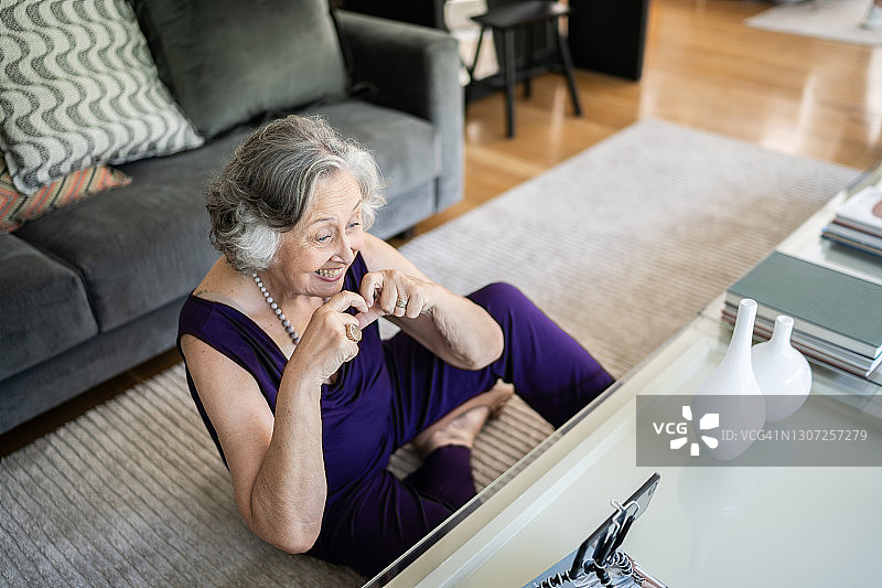 快乐的老女人在家用智能手机打视频电话图片素材