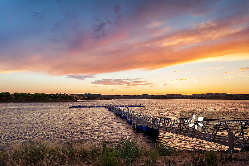 日落时分，Alqueva湖上的码头呈现出五彩缤纷的风景。欧洲葡萄牙的阿连特霍旅游目的地。图片素材
