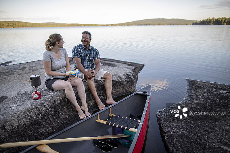 缅因州，一对夫妇在独木舟之旅休息时一边做饭一边大笑图片素材