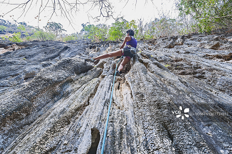 在老挝，一名妇女正在攀登陡峭的石灰岩悬崖图片素材