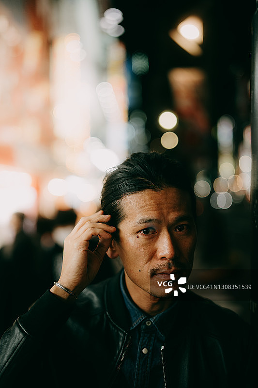 一名日本男子在东京夜晚的城市街道上看着摄像机图片素材