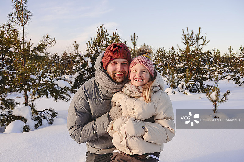 微笑的父亲和女儿穿着暖和的衣服在日落图片素材