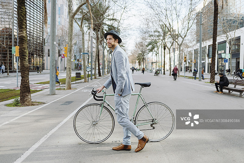 男企业家骑着自行车走在城市的道路上图片素材