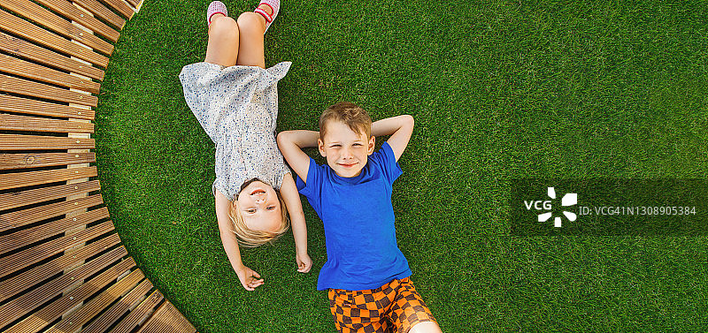 孩子们躺在花园里的绿草地上。孩子们的互动图片素材