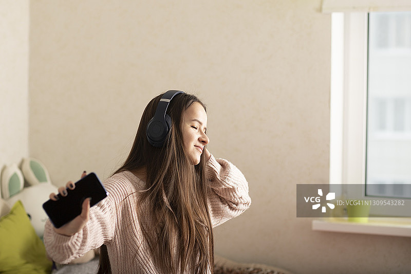青少年和千禧一代，学生戴着耳机在她的房间里跳舞图片素材