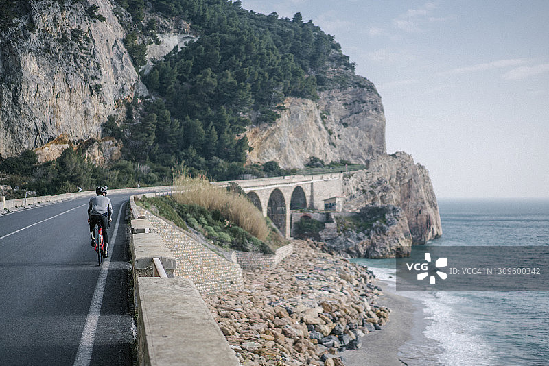 公路自行车骑沿着海岸线和悬崖的狭窄道路图片素材
