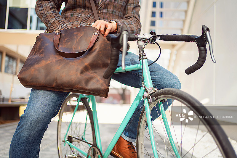 低角度的一个不认识的人检查东西在他的皮包，而坐在自行车上图片素材