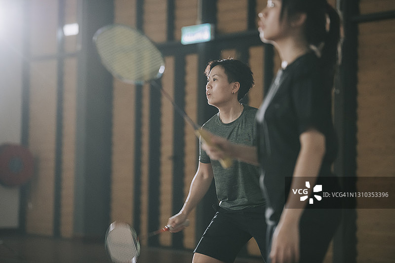 一对亚洲中国女子羽毛球运动员在羽毛球场上比赛图片素材