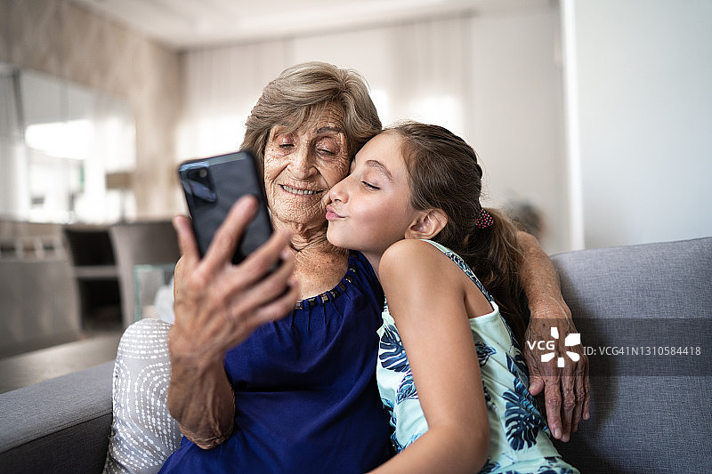 和奶奶在家用智能手机自拍的女孩图片素材