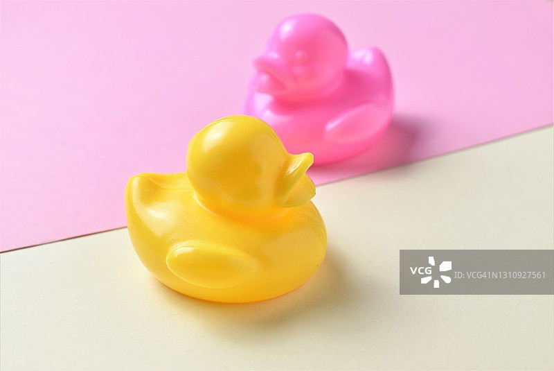 粉红色和黄色的橡皮鸭子在黄色和粉红色的背景上图片素材