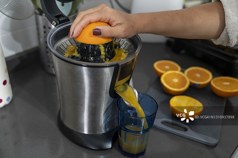 用电动榨汁机榨鲜橙汁的女人图片素材
