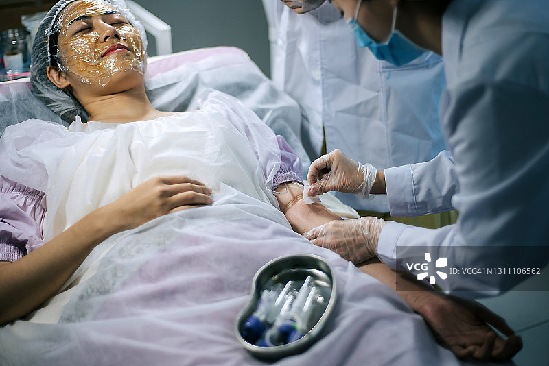 临床应用病人手臂静脉麻醉的亚裔华裔女护士图片素材
