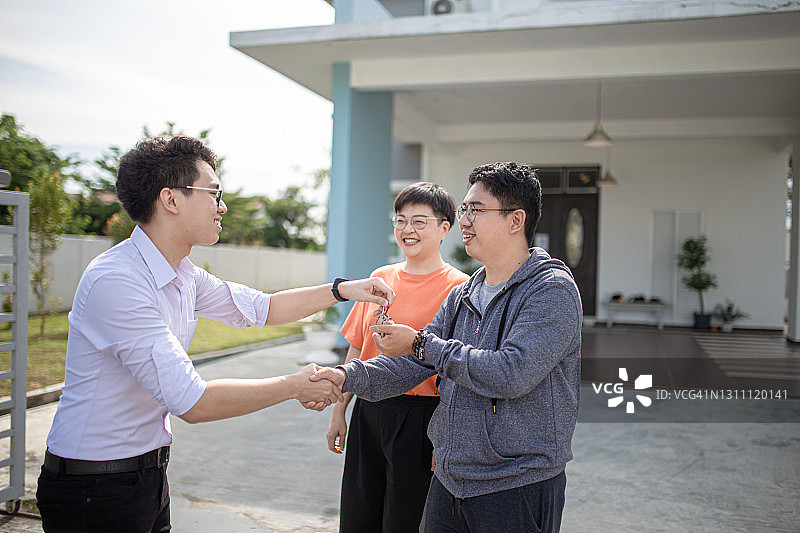 亚洲华人家庭搬进新房子，从房地产经纪人那里得到了房子钥匙图片素材