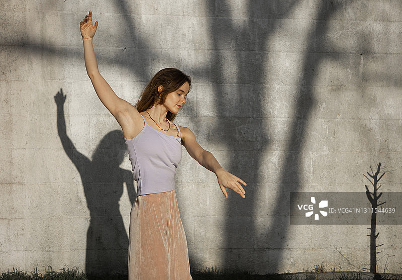 举起双臂对着墙跳舞的女人图片素材