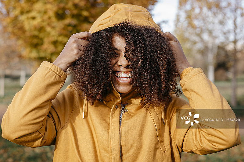 在秋天的公园里，兴高采烈的黑人妇女拿着夹克兜帽图片素材