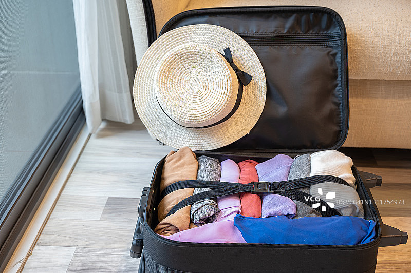 在假期旅行前，打包整理衣服后打开的行李箱。图片素材