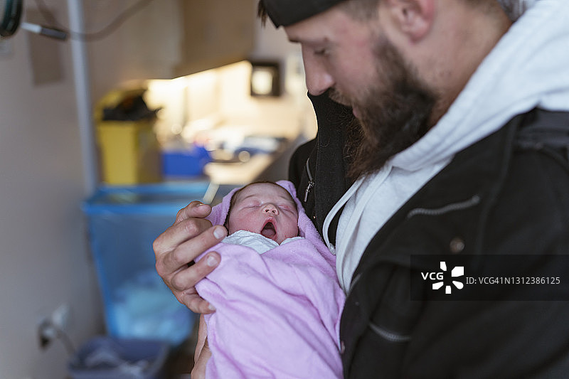 新爸爸抱着刚出生的女儿在医院分娩图片素材