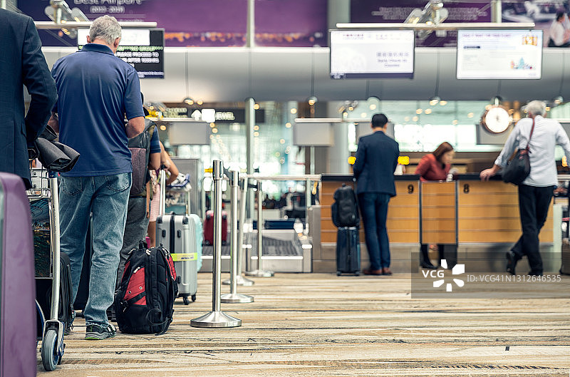 旅客们在机场排队托运行李。图片素材