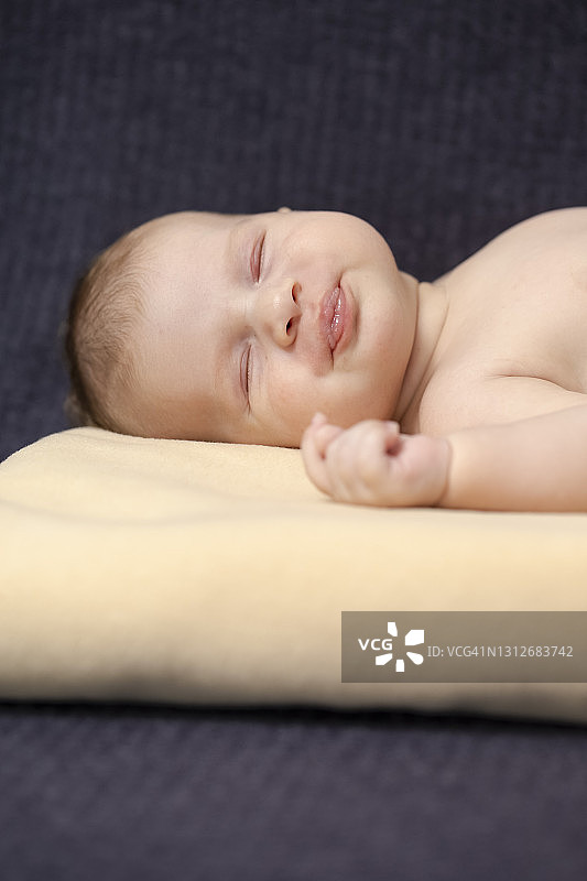 新生儿的概念。微距拍摄在浅黄色毯子上的婴儿和假人安静地睡觉。垂直的图像图片素材