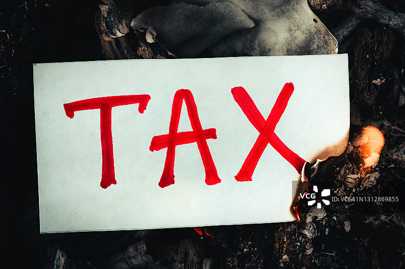 “税”这个红字写在白纸上，在火焰中燃烧。家庭预算概念、期限、财务报告及时偿还债务图片素材