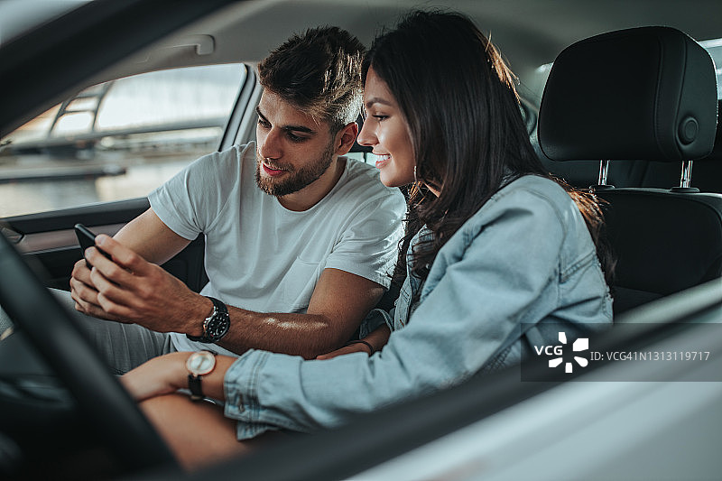 女性和她的男友坐在车里，并使用科技图片素材