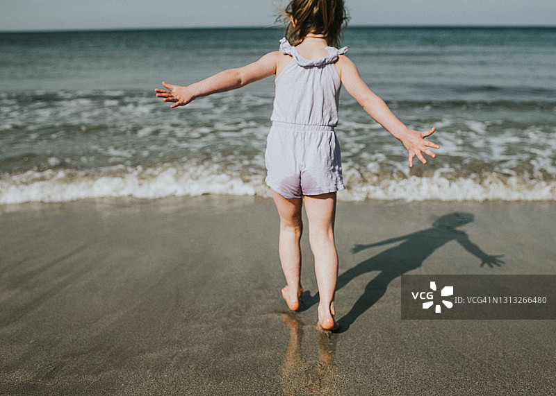 年轻的女孩在潮湿的海滩上跑向大海图片素材