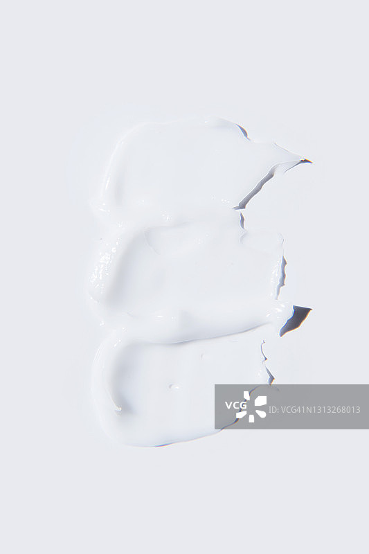 液体纹理涂抹的白色奶油在白色的背景。平铺，俯视图，拷贝空间。图片素材