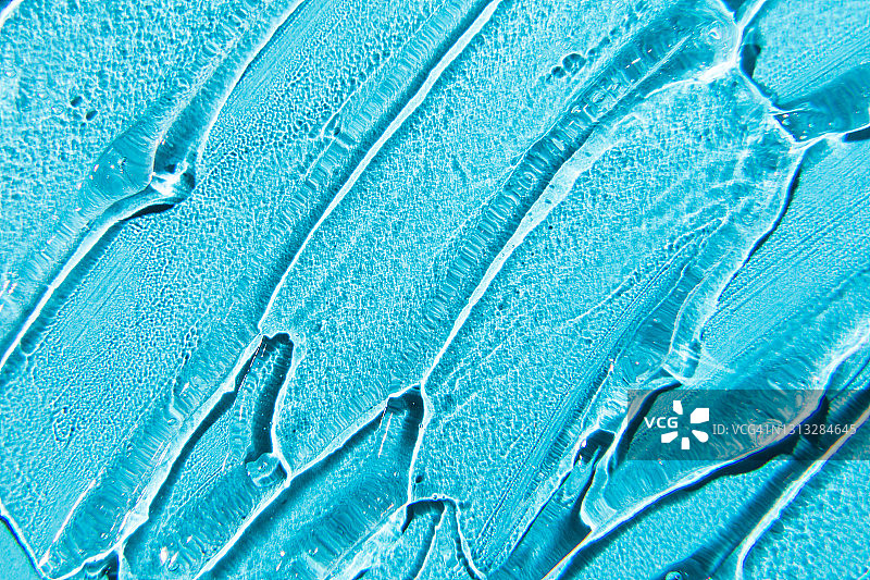 凝胶霜的质地。液体透明质酸凝胶在蓝色背景。图片素材
