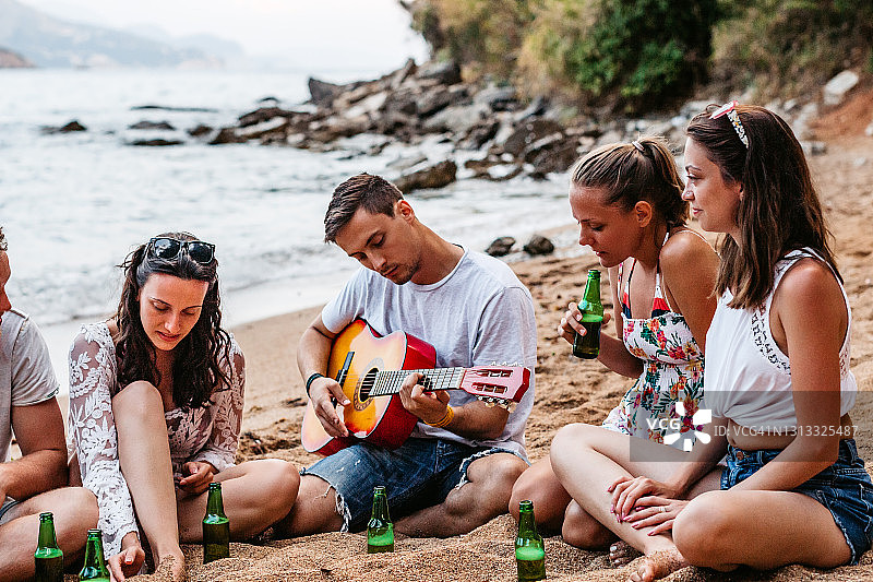 朋友们在海滩上玩吉他，喝啤酒图片素材