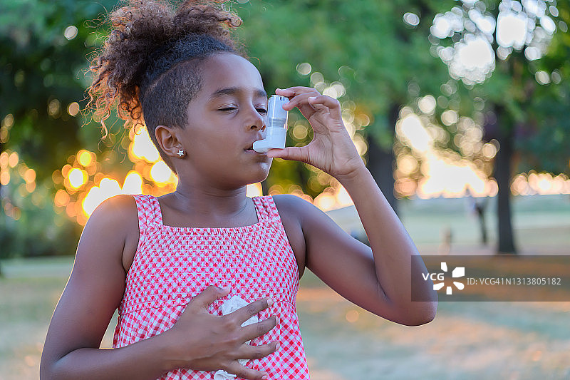 美丽的非洲裔美国小女孩在外面的大自然中有哮喘的问题。图片素材