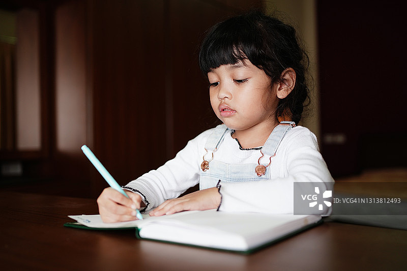 亚洲学生小孩女孩晚上在家里做作业图片素材