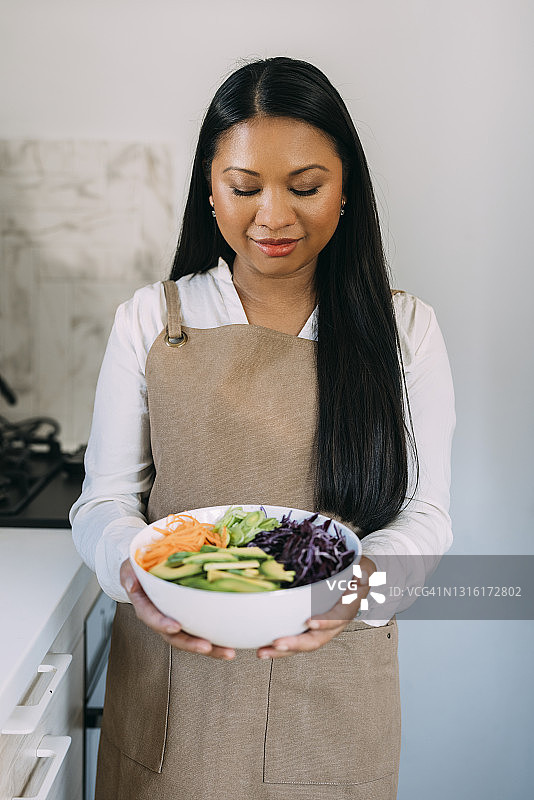 年轻美丽的亚洲女人准备在她的厨房美味的一餐图片素材