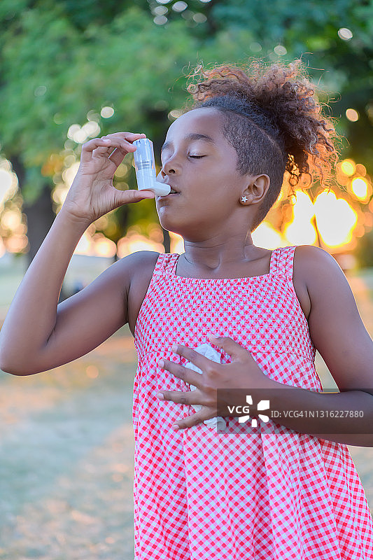 美丽的非洲裔美国小女孩在外面的大自然中有哮喘的问题。图片素材