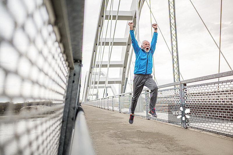 快乐的高级运动员在户外的桥上跑步和跳跃。图片素材
