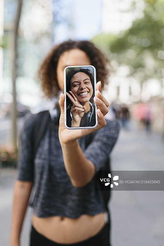 一名女子在城市里用智能手机自拍图片素材