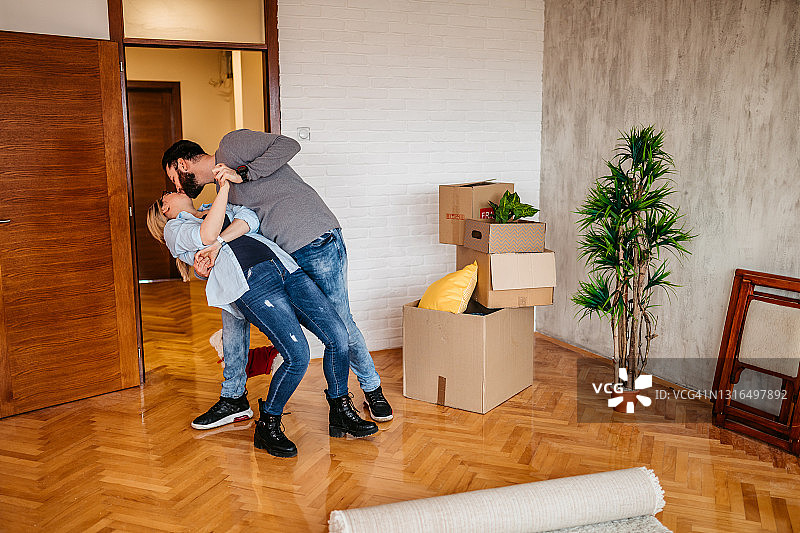 年轻幸福的夫妇在新公寓里跳舞和接吻图片素材