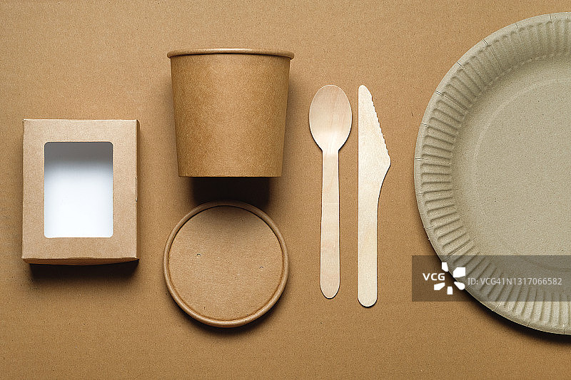 可降解的一次性餐具，由可回收的塑料和纸在米色背景。保护、关怀、环保的理念。环保可持续的生活方式。图片素材