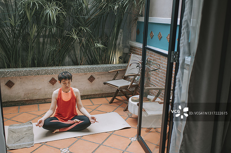 亚洲华人中年妇女瑜伽调解在家放松锻炼，周末休闲时间在后院图片素材