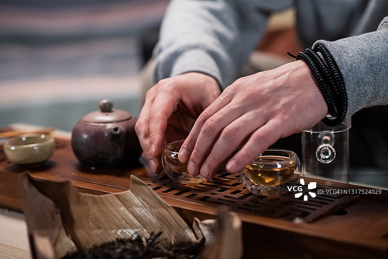 一位东方大师在茶馆为客人举行茶道。特写一套茶具和一个竹制托盘图片素材