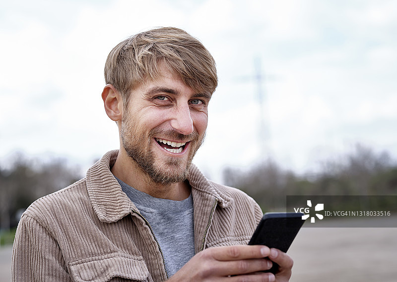 金发微笑的男人拿着智能手机图片素材