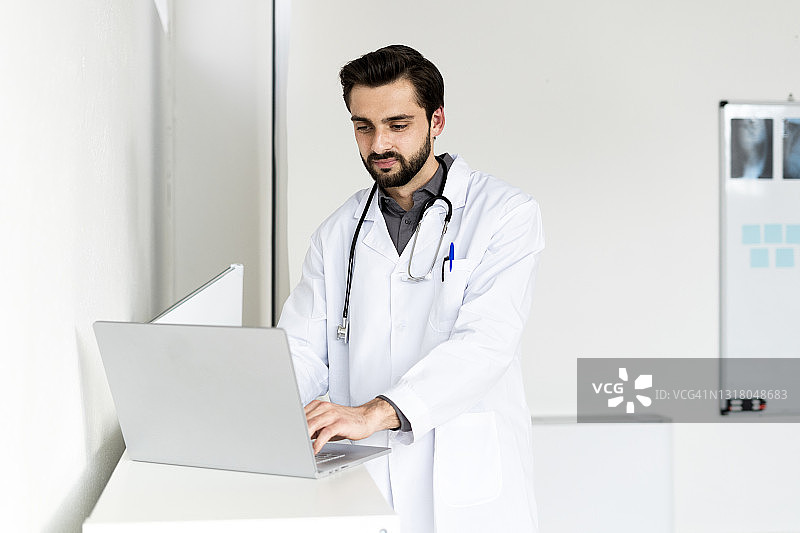 英俊的男医生在医院用笔记本电脑图片素材