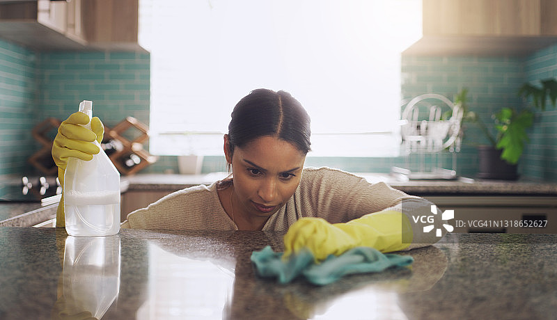 一张年轻女子在家里擦洗厨房柜台的照片图片素材