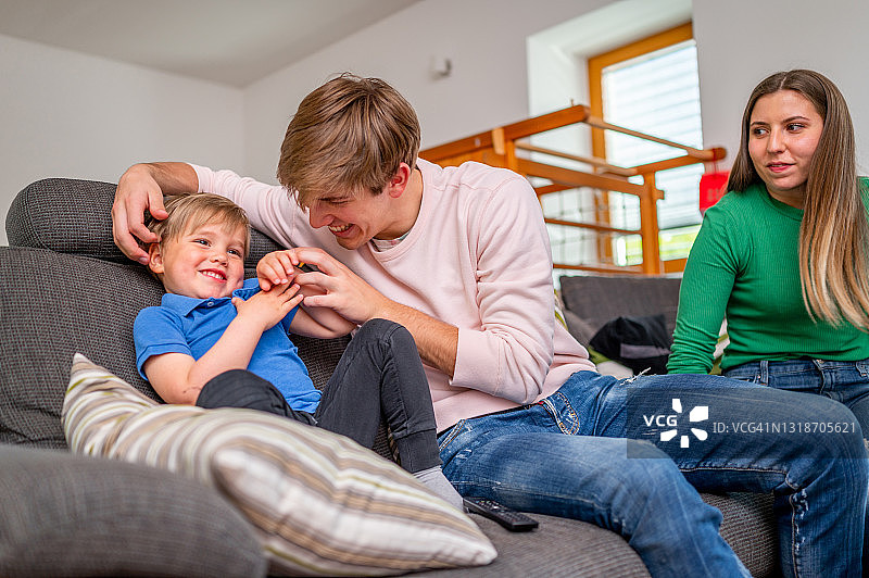 一个年轻的家庭和一个孩子在客厅里玩耍图片素材