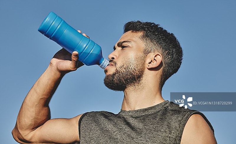 一个运动的年轻人在户外运动喝水的低角度镜头图片素材