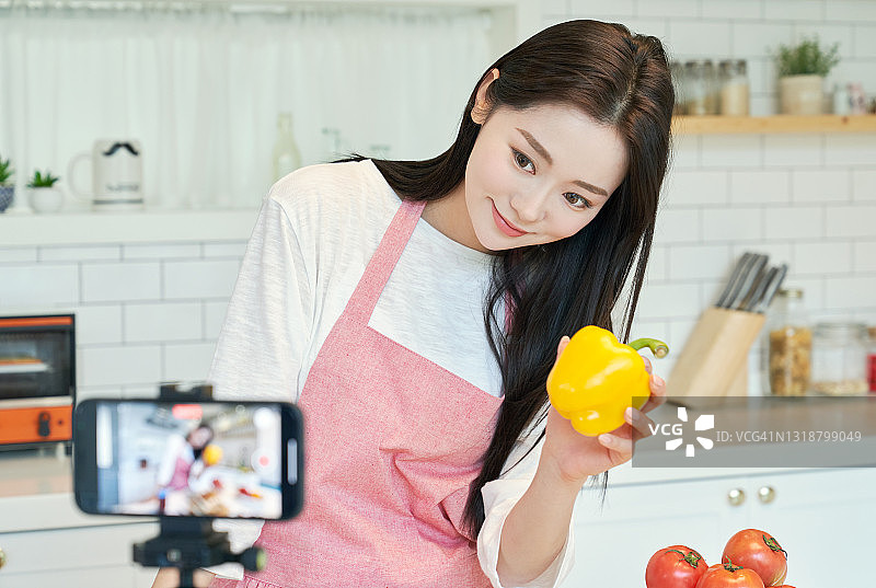 一个在厨房拍摄烹饪视频的女人图片素材
