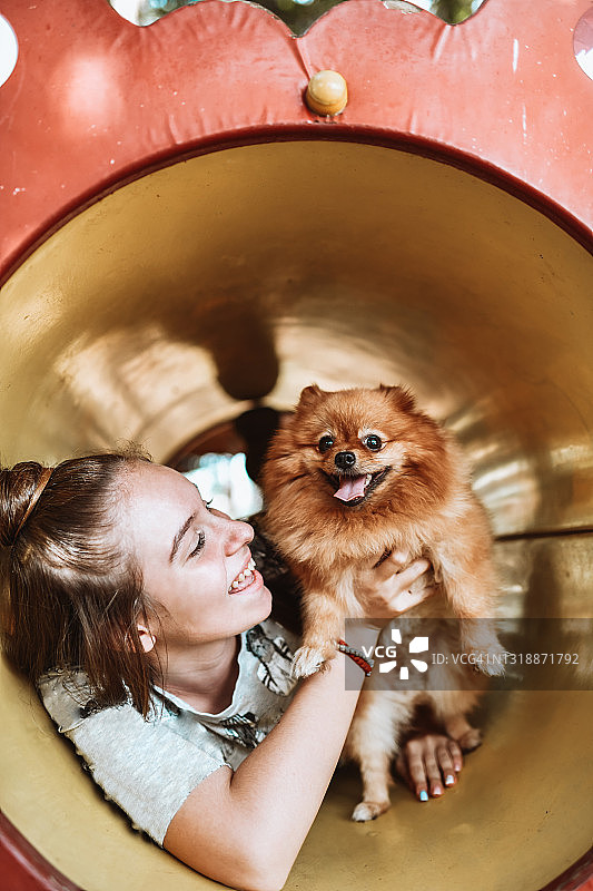 可爱的女性花时间在操场隧道与博美犬图片素材