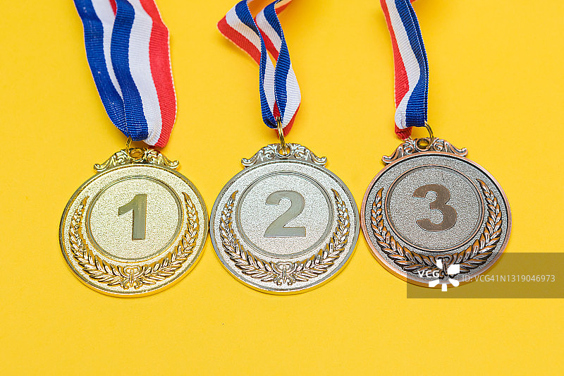 金牌，银牌和铜牌的体育成就的第一，第二和第三名，在黄色的背景。图片素材