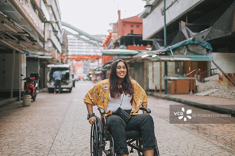 亚洲印度美丽的妇女与残疾使用轮椅探索市区在吉隆坡图片素材