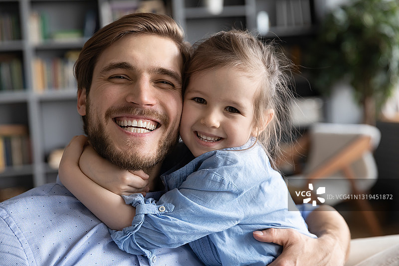快乐的年轻父亲和小女儿拥抱的肖像图片素材