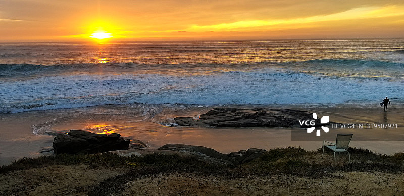 孤独的冲浪者在日落走到海滩冲浪板图片素材